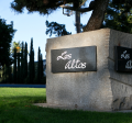Large granite marker that says 'Los Altos' sitting on grass with trees in the background 
